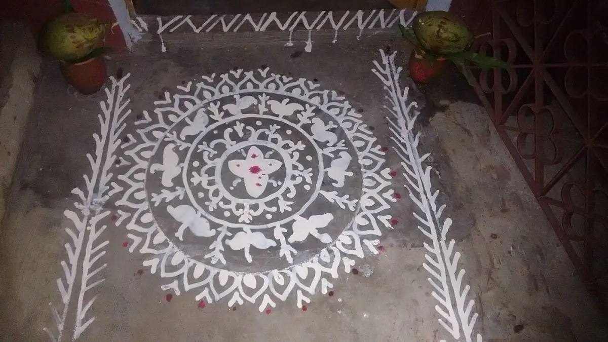 Alpana drawn at the doorstep in rice paste and chalk water.
