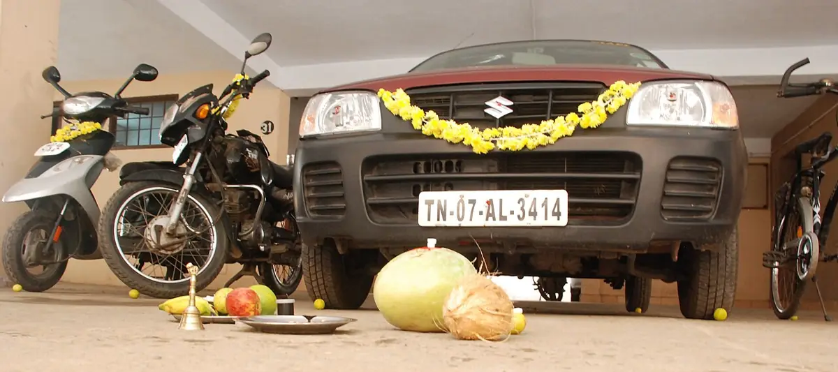 Vehicles garlanded for Ayudha Puja, with an ash gourd ready in front.