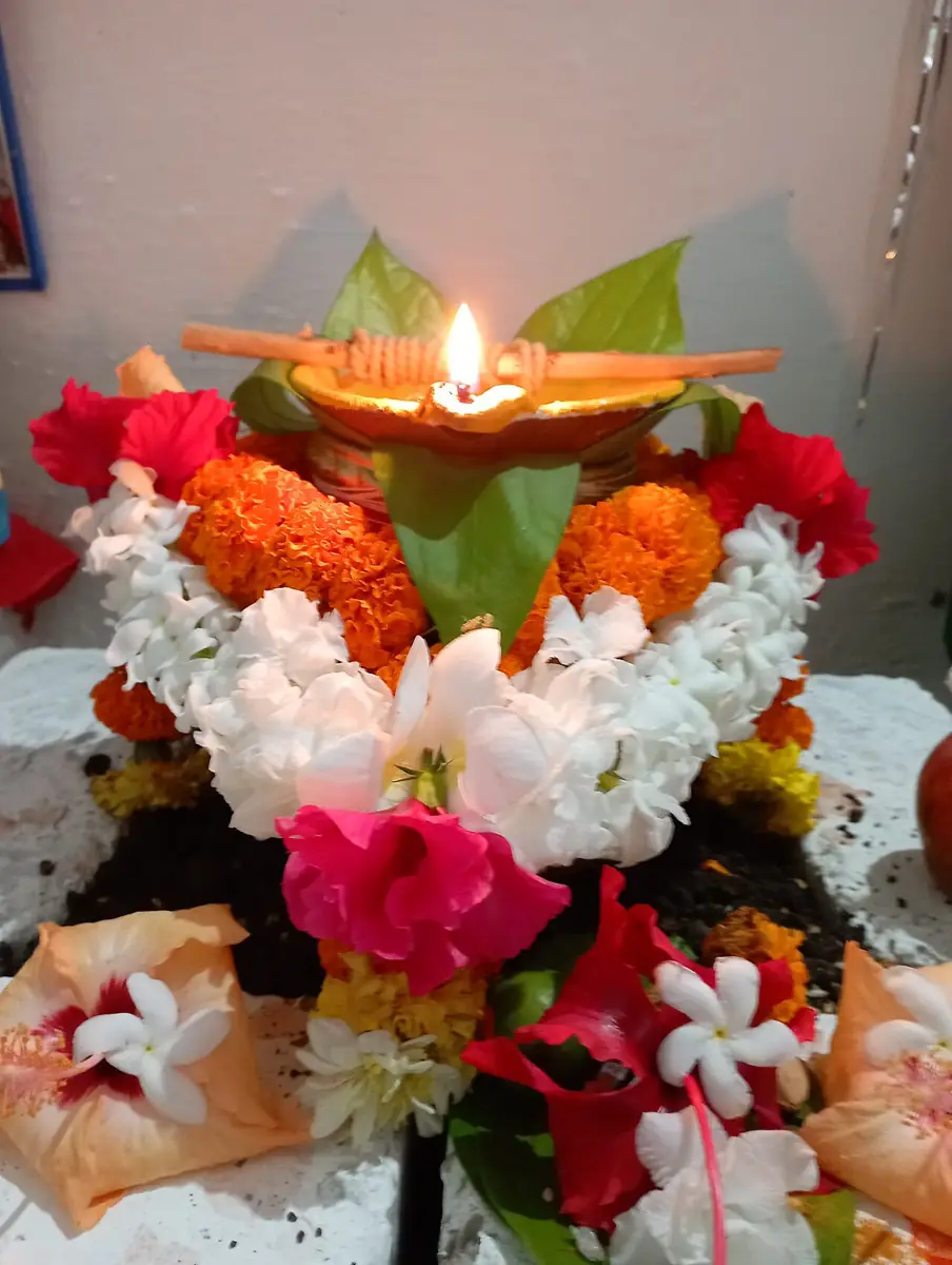 A kalash (ghat) with a lamp, leaves and flowers, set up for worship.