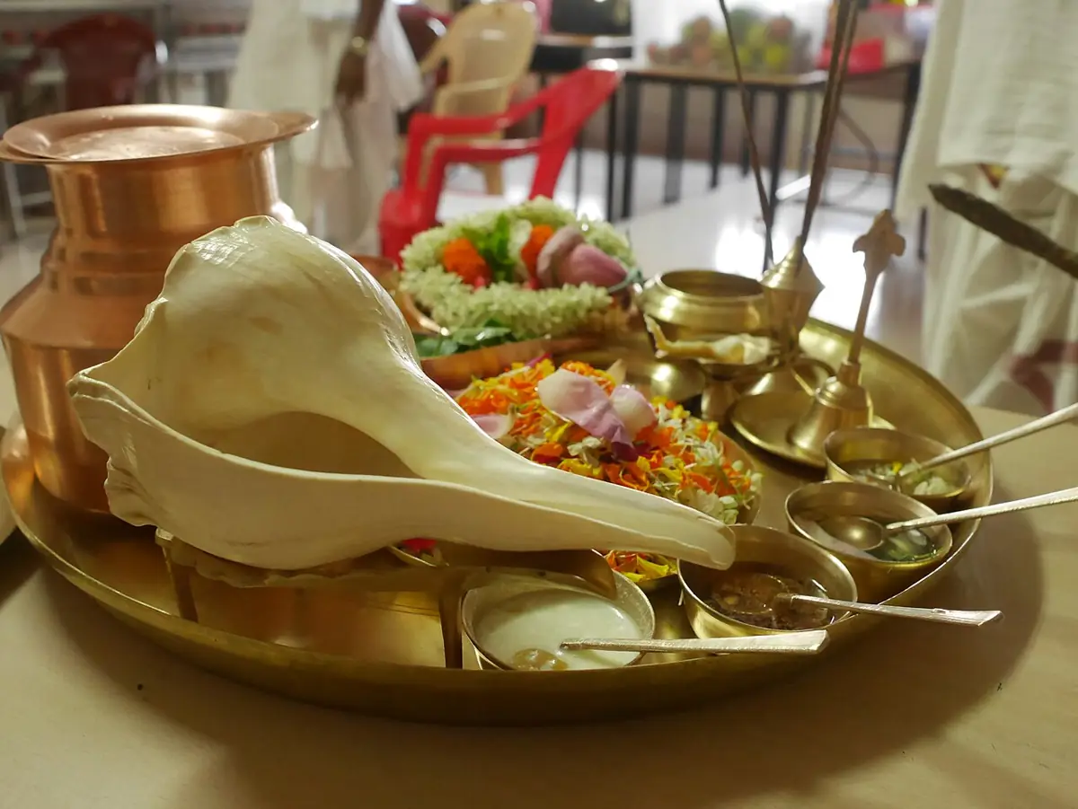 A worship plate with a conch, lamp and offerings.