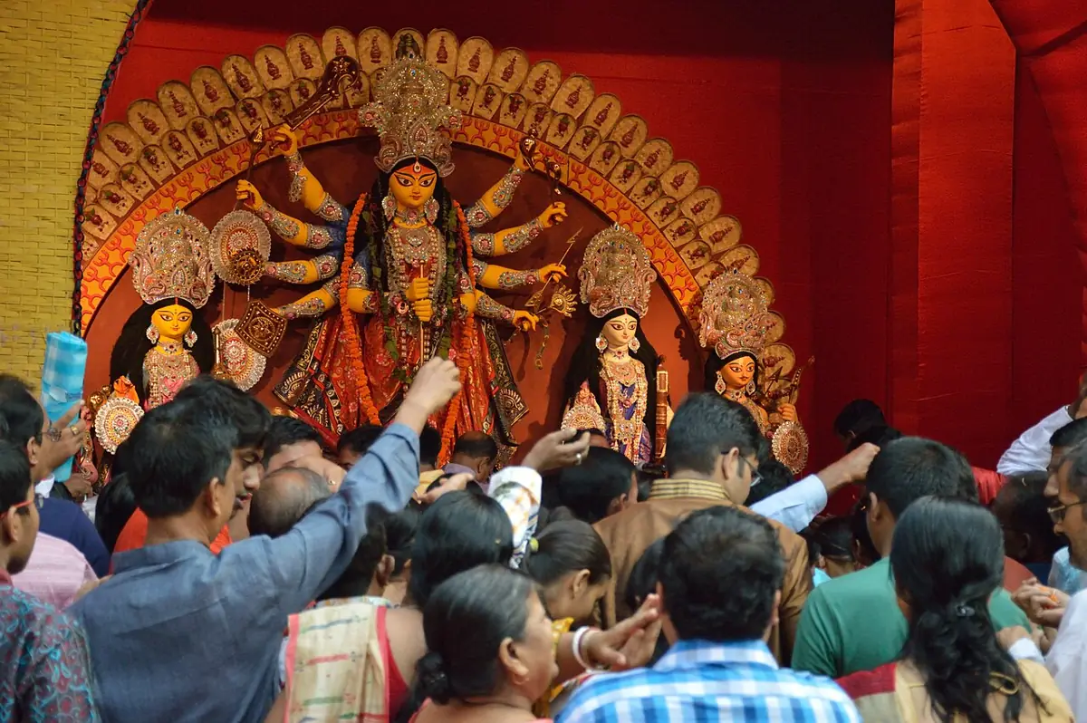 Devotees raise flowers for pushpanjali on Maha Ashtami at a Kolkata pandal.
